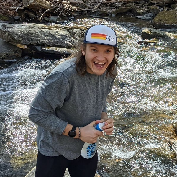 Photo of Brett holding a water filter in a stream